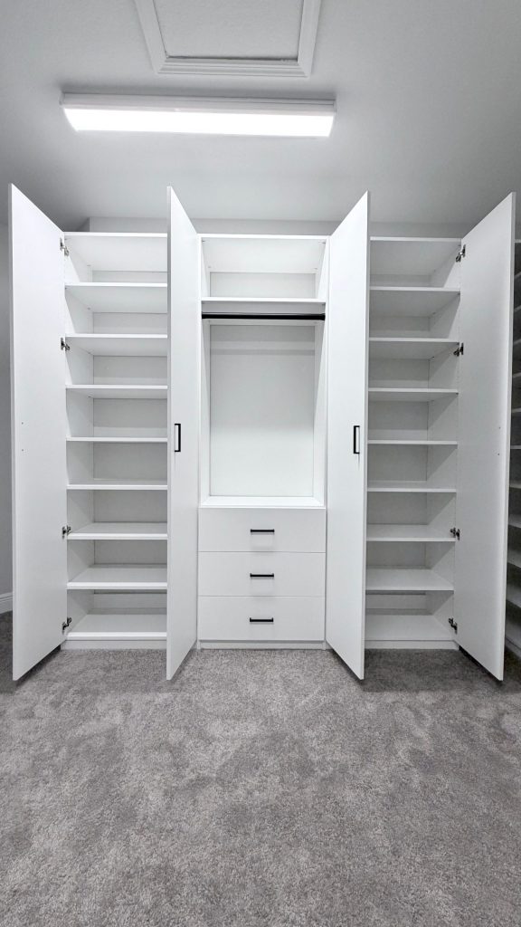 Custom walk-in closet with doors, drawers, corner shelves, black hardware in Lithia, Florida.