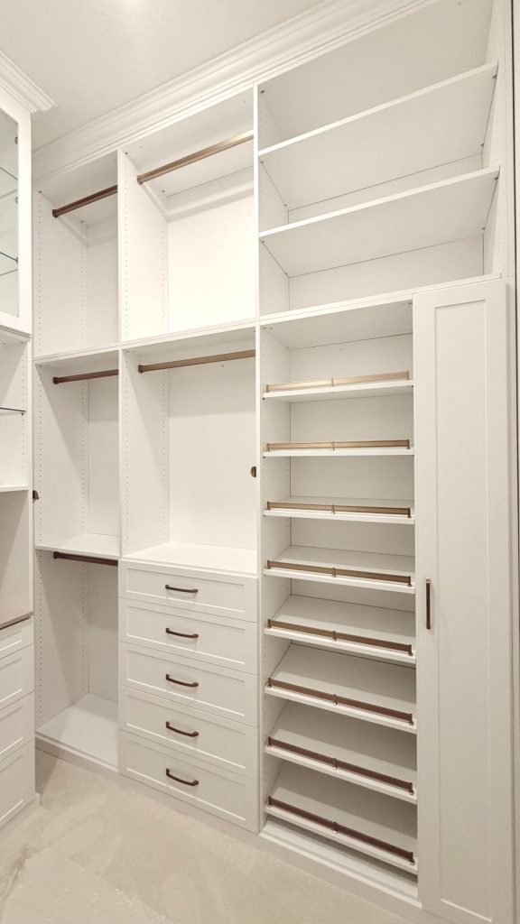 Custom walk-in closet with doors, drawers, glass, jewelry / accessory tray, matte colors, shoe fence, thermofoil, gold hardware in Zephyrhills, Florida.