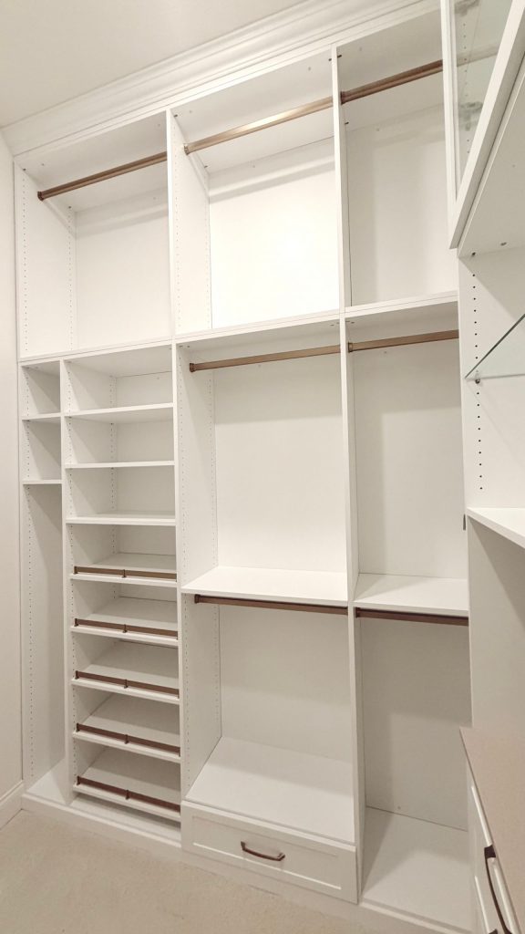 Custom walk-in closet with doors, drawers, glass, jewelry / accessory tray, matte colors, shoe fence, thermofoil, gold hardware in Zephyrhills, Florida.