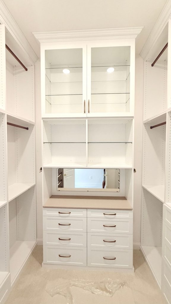 Custom walk-in closet with doors, drawers, glass, jewelry / accessory tray, matte colors, shoe fence, thermofoil, gold hardware in Zephyrhills, Florida.